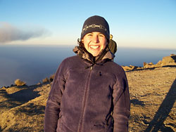 Student at the summit of a volcano with the vista in the background.